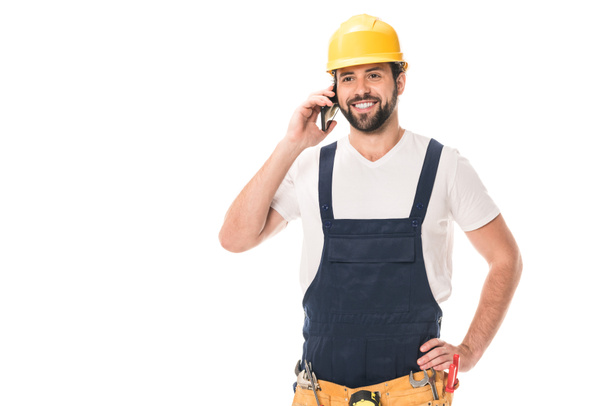 happy handsome construction worker in hard hat talking by smartphone isolated on white - Photo, Image