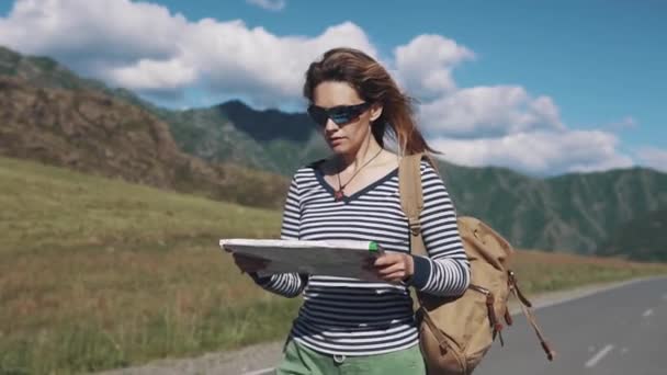 Portret van een reiziger vrouw close-up. het toeristische meisje met een papieren kaart in haar handen loopt langs de snelweg - Video