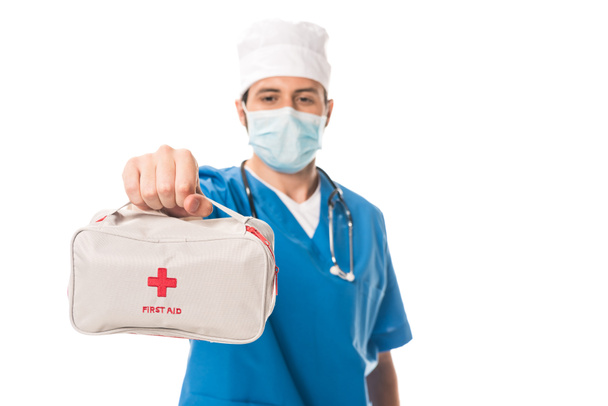 Крупный план врача в медицинской маске, держащего аптечку, изолированную на белом
 - Фото, изображение