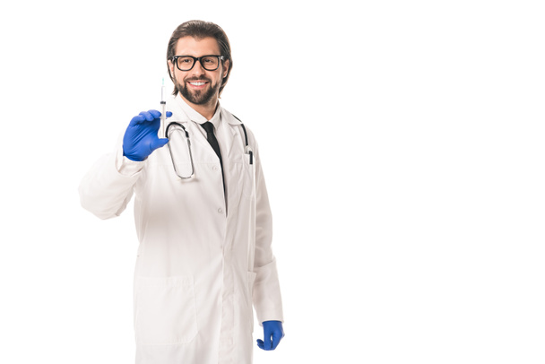 uśmiechający się lekarza w Rękawice medyczne, trzymając strzykawkę na białym tle - Zdjęcie, obraz