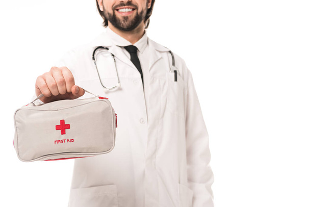 ritagliato colpo di sorridente medico in possesso di kit di pronto soccorso isolato su bianco
 - Foto, immagini