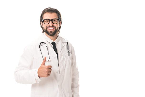 handsome doctor in eyeglasses and white coat showing thumb up and smiling at camera isolated on white - Photo, Image
