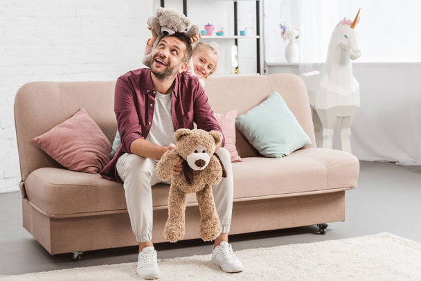 pai e filha brincando com ursinhos de pelúcia no sofá
 - Foto, Imagem