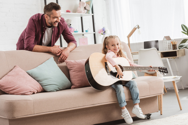 Vater und Tochter haben Spaß und spielen auf der Gitarre - Foto, Bild