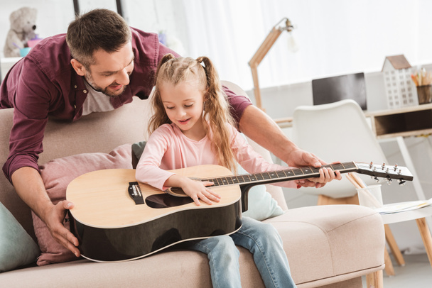 father and daughter playing on guitar at home - Foto, afbeelding