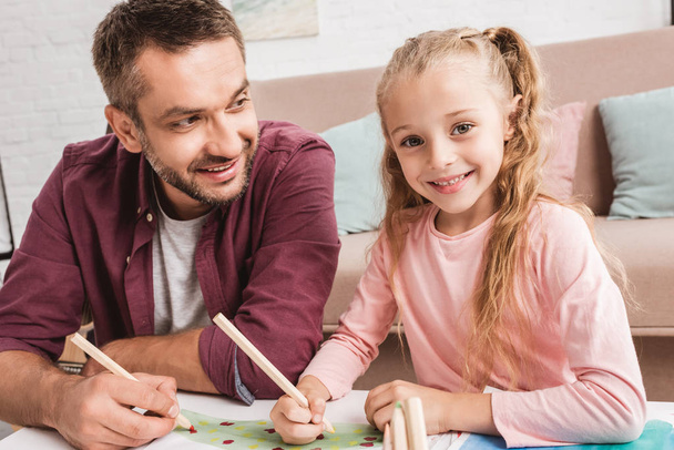 cheerful dad and daughter having fun and drawing at home - Foto, imagen