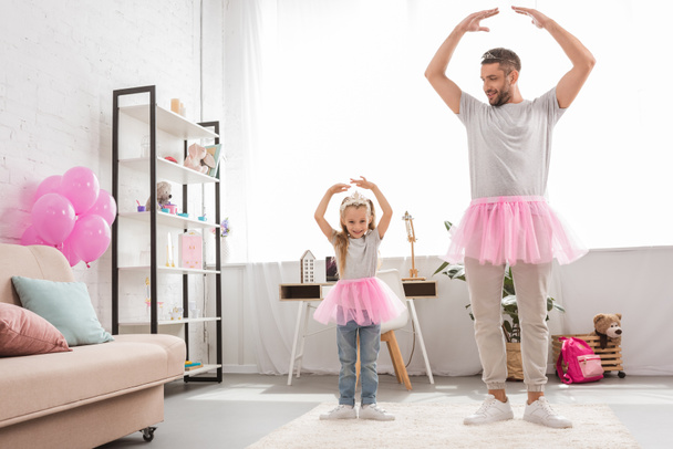 father and daughter in pink tutu skirts dancing like ballerinas - 写真・画像