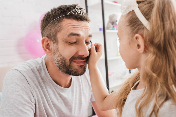 side view of daughter doing makeup to father - Foto, Imagem