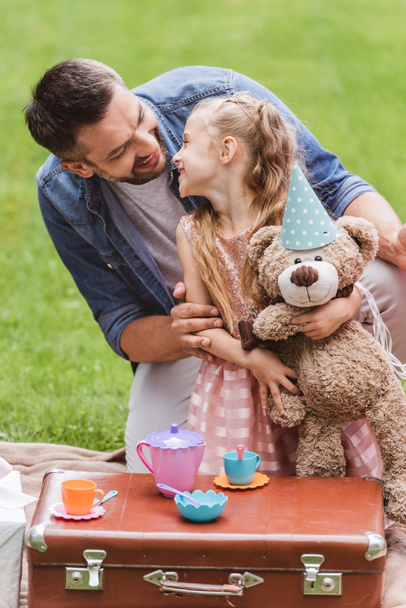 father and daughter with teddy bear playing tea party at lawn - Foto, Imagen