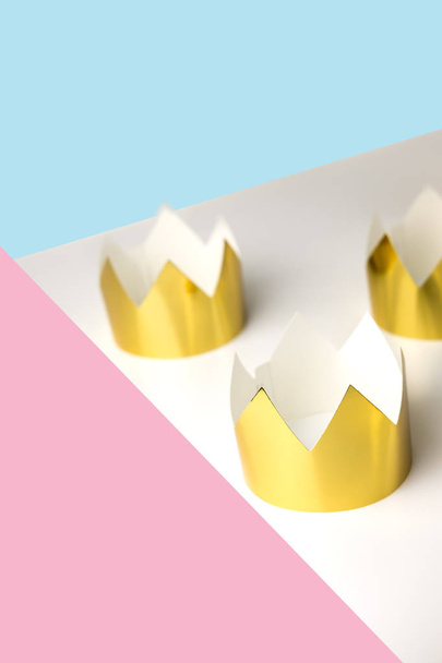 Cardboard golden crowns lying on a white table. Minimalistic style. Place for text. Copyspace. - Foto, Imagen