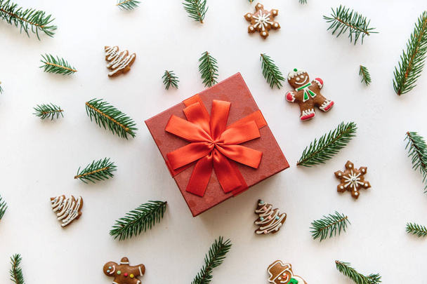 Regalo de Navidad o Año Nuevo en una caja roja. Cerca hay varias cosas de vacaciones, incluyendo galletas de jengibre
. - Foto, Imagen