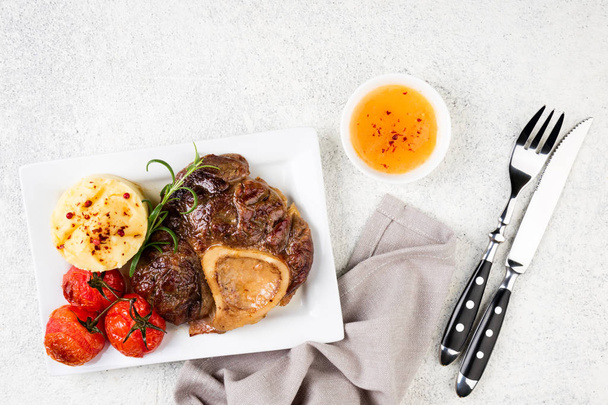準備牛肉ステーキ オッソ ・ ブッコ、マッシュ ポテトとトマトの白いテーブルの上。平面図です。コピー スペース - 写真・画像