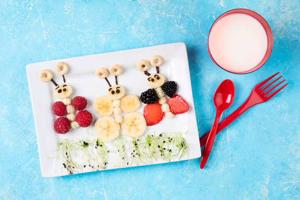 Panini e latte per la colazione dei bambini. Panini alla farfalla divertenti con bacca, banana, cioccolato, microverde. Cibo sano per bambini. Vista dall'alto
 - Foto, immagini
