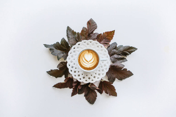 Filiżankę pachnące kawy cappuccino. W pobliżu leżą jesienne liście. - Zdjęcie, obraz