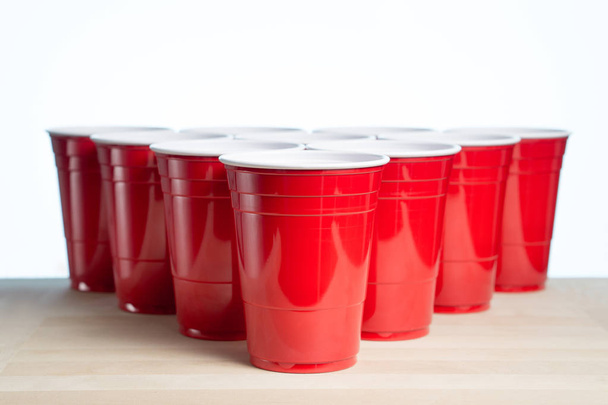 Red party cups on wooden table for beer pong tournament isolated on white. College alcohol containers with free empty blank copy space for text. Event marketing and promotion background template. - Photo, Image