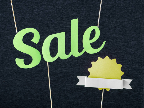 Fun summer sale design for promo. Hanging green letters and yellow badge with ribbon cut from cardboard paper on wooden stick. Fresh and fun marketing look. Free blank empty copy space for text. - Photo, Image