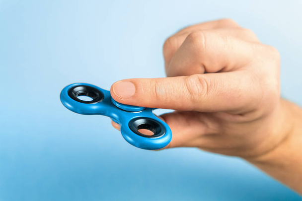 Fidget spinner azul entre os dedos
 - Foto, Imagem