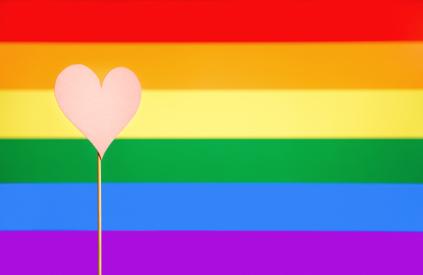 Gay pride and LGBT background. Rainbow flag design template with copy space. Heart cut from cardboard paper on wooden stick. Sexual minority, homosexuality and equal rights. Handmade love symbol. - Photo, Image