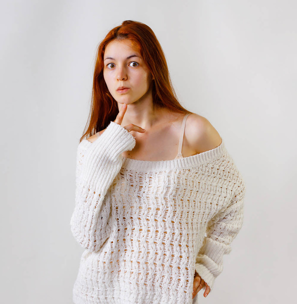 Think girl, feeling and emotions, pretty girl face expression, compress the lips with finger, dressed in knitted sweater looking at camera, naked shoulder, grey background copy space. - Foto, Imagen
