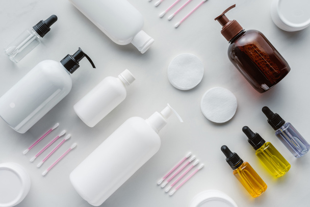 flat lay with bottles of cream, natural oils and cosmetic pads on white surface, beauty concept - Photo, Image