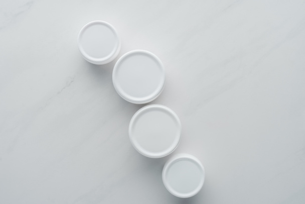 vista superior de botellas de crema en la superficie blanca, concepto de belleza
 - Foto, imagen