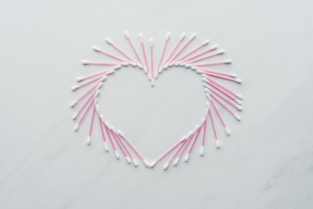 top view of cotton swabs in shape of heart on white surface, beauty concept - Photo, Image