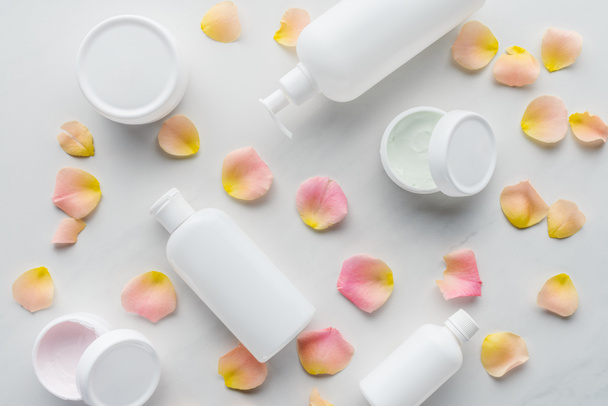 elevated view of bottles of cream and rose petals on white tabletop, beauty concept - Photo, Image