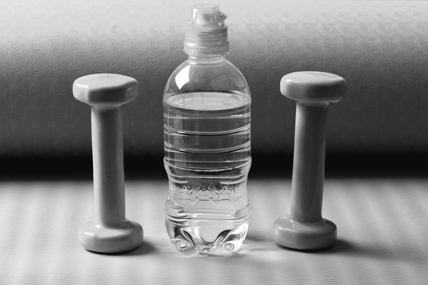Dumbbells in cyan color next to water bottle - Фото, изображение