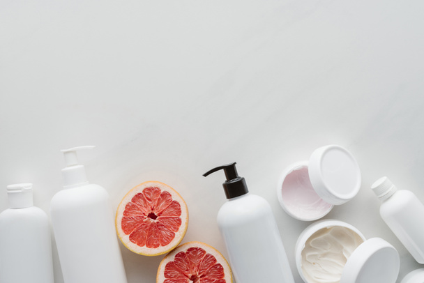 flat lay with containers of lotion and pieces of grapefruit on white surface, beauty concept - Fotografie, Obrázek