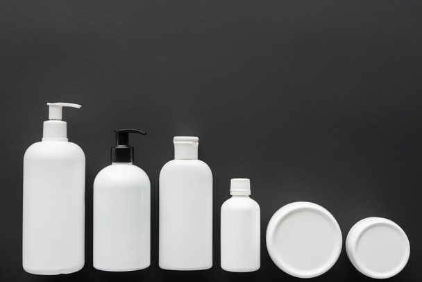 top view of white plastic bottles of cream isolated on black, beauty concept - 写真・画像
