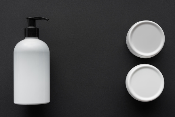 top view of bottles of lotion and cream isolated on black, beauty concept - Photo, Image