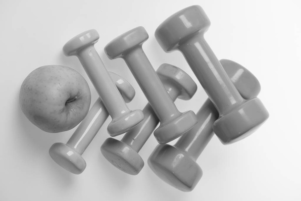 Health regime and fitness symbols. Dumbbells near green apple - Fotografie, Obrázek