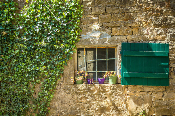 Une ancienne fenêtre avec volets verts sur le mur de pierre de la maison
. - Photo, image