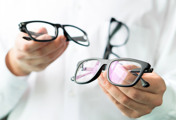 眼鏡レンズを比較するか、眼鏡で顧客のさまざまなオプションを表示します。医師の目のために、新しいメガネを示す。多くの眼鏡で白衣でプロの検眼医. - 写真・画像