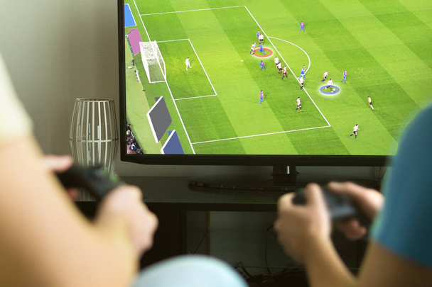 Two guys playing imaginary multiplayer soccer or football video game with console and tv. Guys night, party and weekend concept. - Foto, Imagen