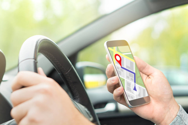 Ο άνθρωπος οδήγηση αυτοκινήτου και χρησιμοποιώντας online χάρτη και Gps εφαρμογή σχετικά με έξυπνο τηλέφωνο. Πλοήγηση με κινητές app. μέσα δείτε σε αυτοκίνητο στο χέρι εκμετάλλευση smartphone. - Φωτογραφία, εικόνα