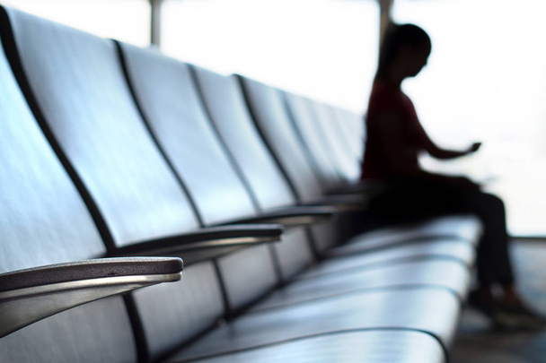 Concept de vol retardé et annulé. Silhouette femme regardant sa montre dans le terminal de l'aéroport pour voir l'heure dans la salle d'attente de l'aéroport et salon de départ
. - Photo, image