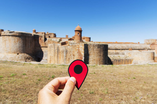 closeup of a caucasian man with a red position marker in front of the fortress Fort de Salses, built in the 15 century, in Salses-le-Chateau, France, property of the French state - Photo, Image