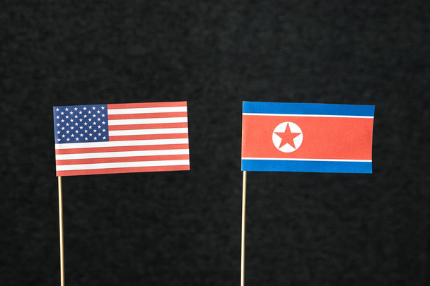 Флаг Соединенных Штатов Америки (США) и Северной Кореи сделан из бумаги на деревянной палочке на темном фоне
. - Фото, изображение