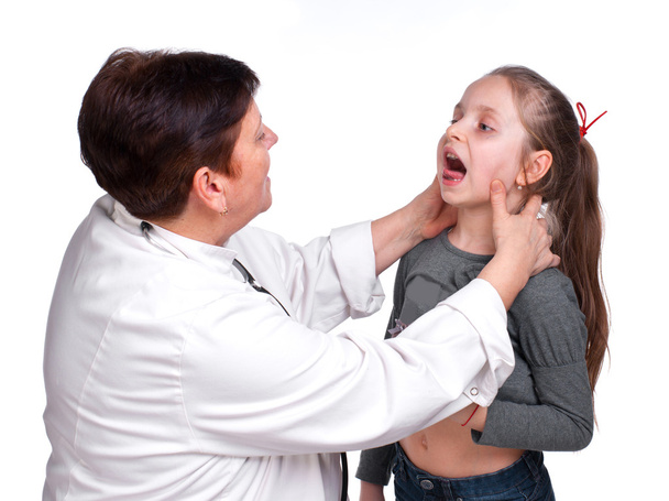 Vanhempi lastenlääkäri tutkimassa tytön kurkkua
 - Valokuva, kuva