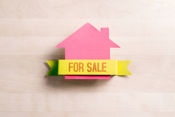 Σπίτι προς πώληση. Real estate επιχειρηματική ιδέα. Πωλούν και αγοράζουν σπίτι. Εξοχικό σπίτι από χαρτόνι χαρτί σε ξύλινο τραπέζι. - Φωτογραφία, εικόνα