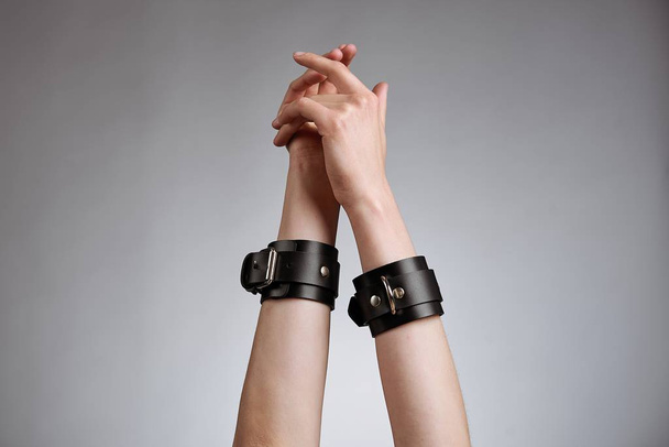 hands of woman in leather handcuffs against studio background  - Fotografie, Obrázek
