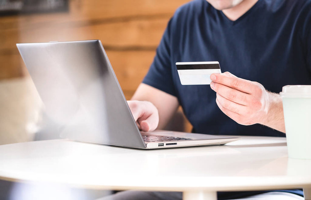 Man houdt van creditcard en bank informatie of identificatie nummers met laptop typen. E-commerce en online shopping concept. - Foto, afbeelding