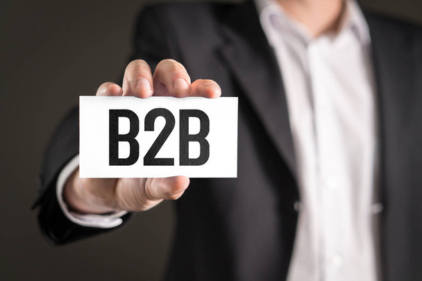 Concetto di marketing B2B e business-to-business. Uomo d'affari in possesso di carta con testo
. - Foto, immagini