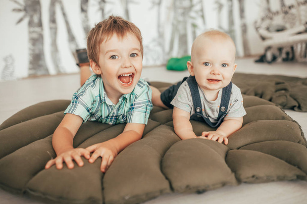 Two brothers lie on carpet, have fun and play. - 写真・画像