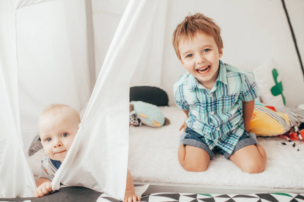 Two brothers sit on carpet in tent, have fun and play. - Fotografie, Obrázek