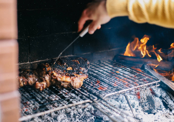 Человек готовит идеальный стейк на открытом огне барбекю
 - Фото, изображение