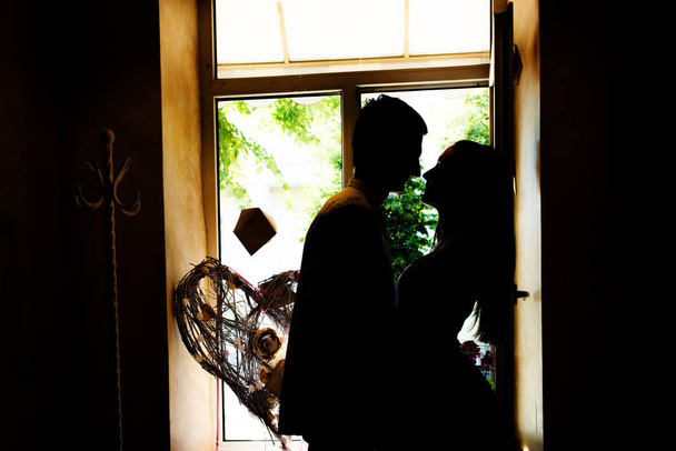 Silhouetten van de pasgetrouwden in het café. Een blik van de liefdevolle paar staan dicht bij elkaar, neus aan neus, raam maken van schaduwen van hen - Foto, afbeelding