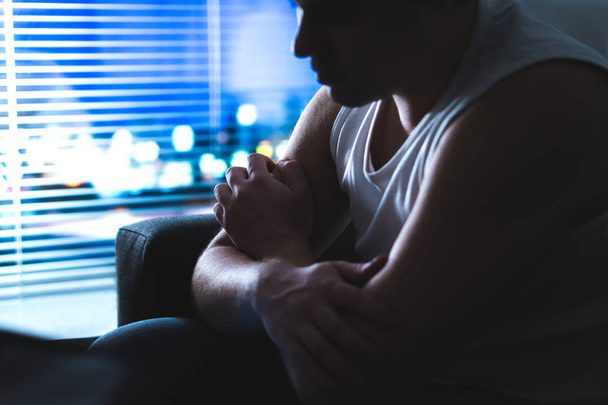 Thoughtful, pensive and contemplating man thinking in dark home at night by the window. Emotional and dramatic mood. Making hard decision. Despair, loneliness or insomnia concept. Young rebel. - Фото, зображення