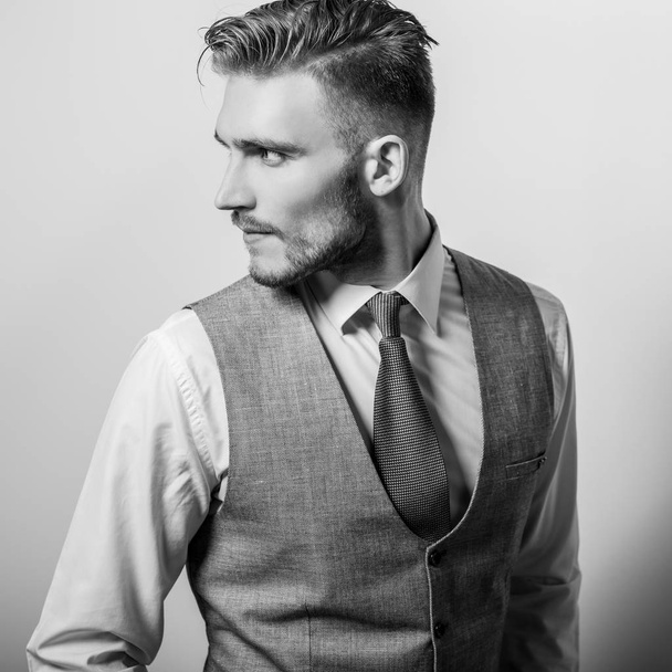 Handsome young elegant man in grey classic vest pose against studio background. - Foto, immagini